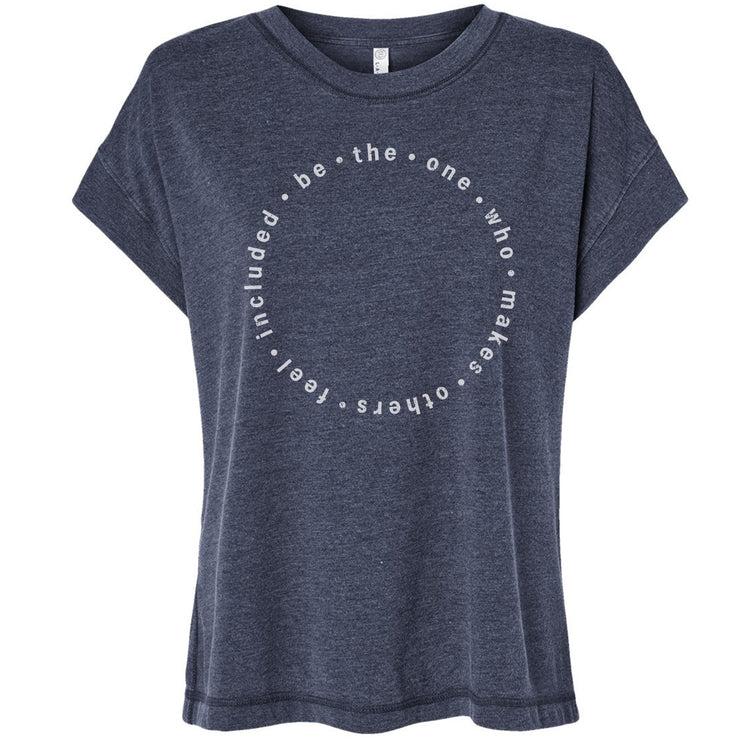 A gray t-shirt with a circular design featuring the text "be the one who makes others feel included" printed on it.