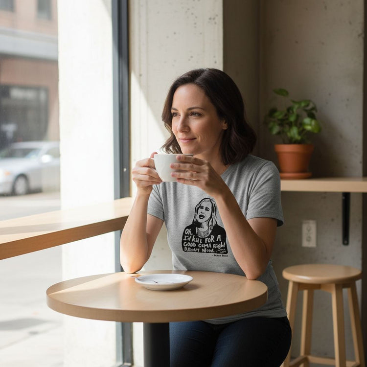 A woman is sitting at a table in a cafe, holding a cup and looking out the window.