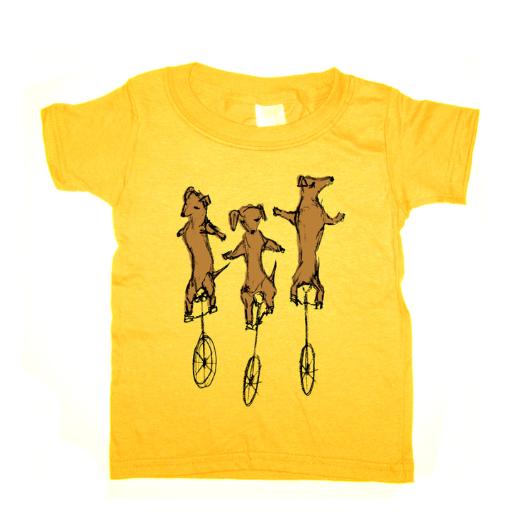A yellow t-shirt with a graphic design depicting three cartoon dogs riding on unicycle wheels.