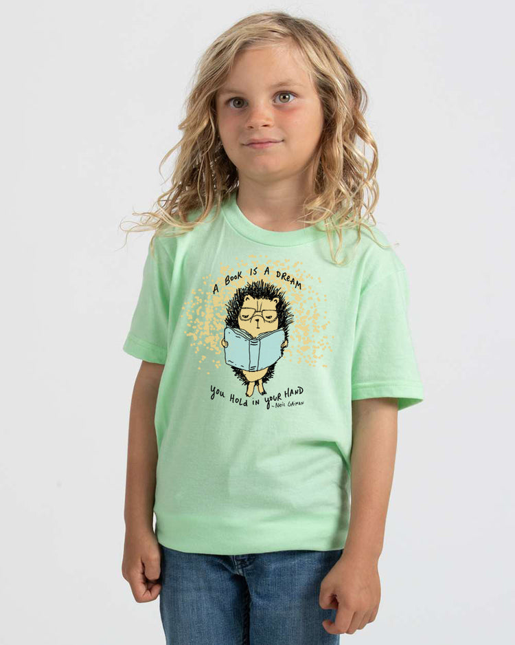 a little girl wearing a green shirt with a picture of a hedge on it