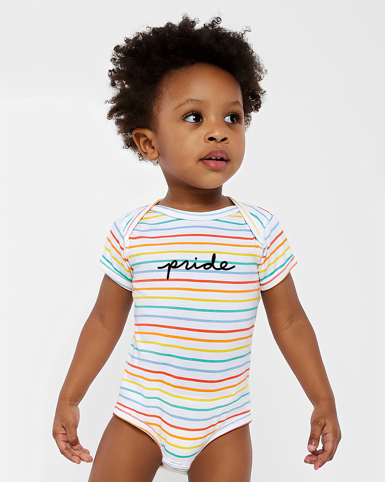 A young child with curly hair wearing a striped bodysuit with the word "pride" written on it.