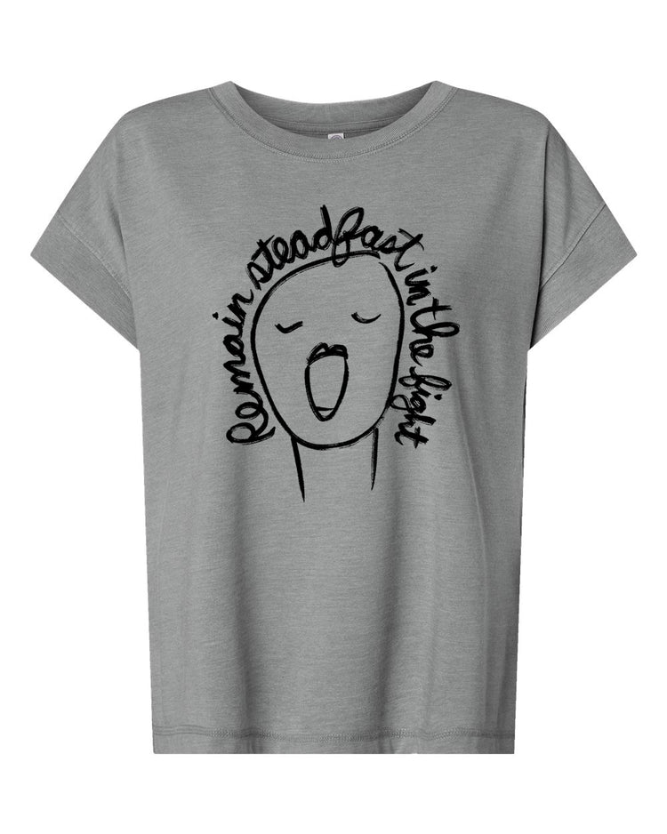 A gray t-shirt with a simple black and white graphic design depicting a face with an open mouth and the text " Remain steady fast in the light" written around the face.