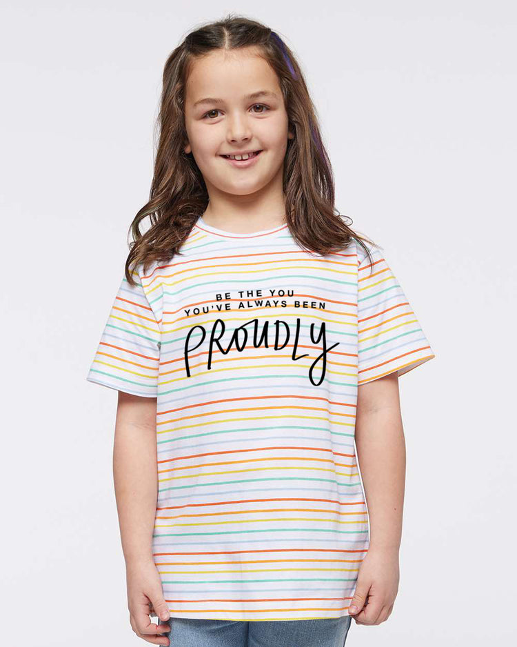 A young girl with long brown hair is smiling and wearing a striped t-shirt with the text "Be the you, you're always been proudly" printed on it.