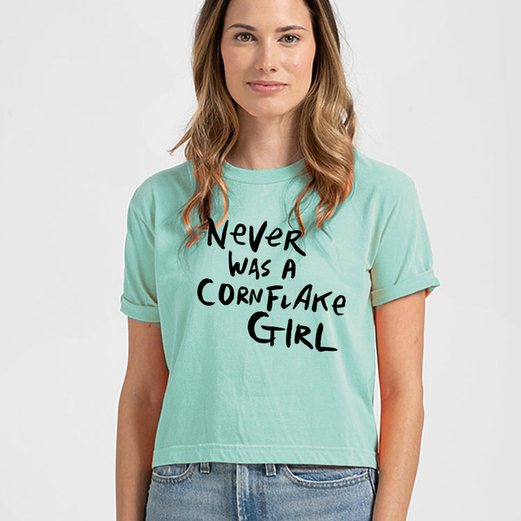 A woman wearing a mint green crop top with the text "Never was a cornflake girl" printed on it.
