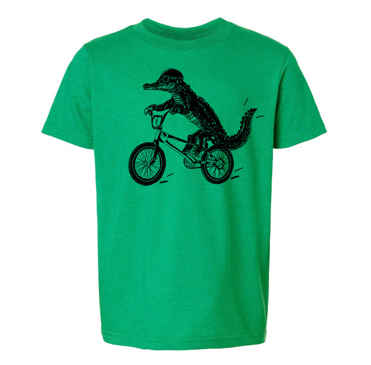 A green t-shirt with a black graphic of a crocodile riding a bicycle.