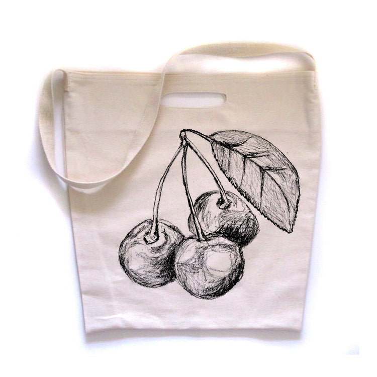 A white tote bag with a black and white illustration of cherries on it.