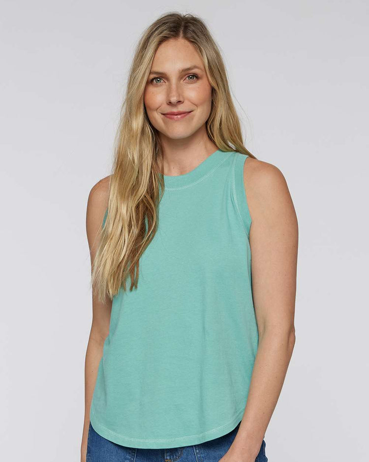 A woman with long blonde hair is smiling and wearing a turquoise sleeveless top.