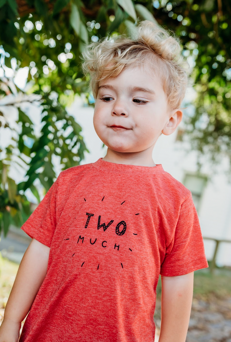 a young boy standing in front of a tree