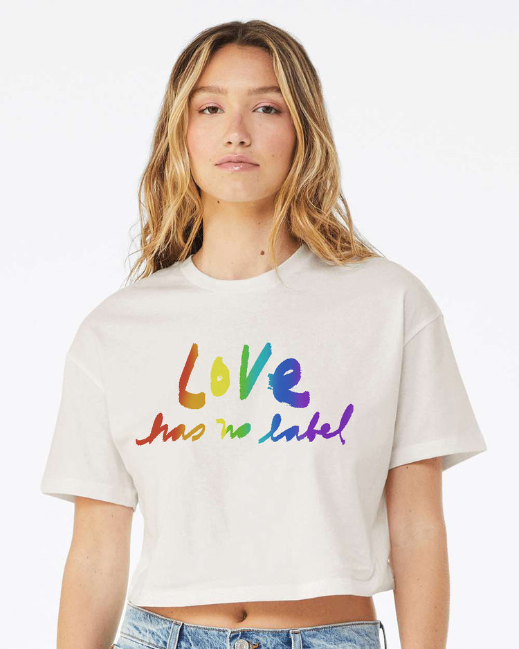 A young woman with long blonde hair wearing a white t-shirt with the text "Love has no label" printed on it.