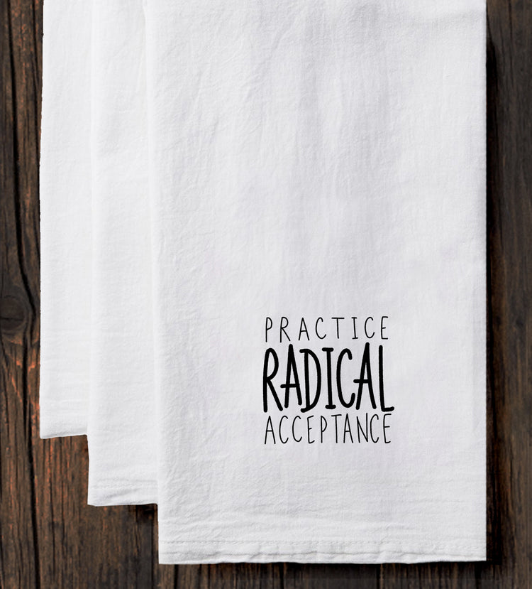 a set of white towels with black text printed on them. The text reads "Practice Radical Acceptance".