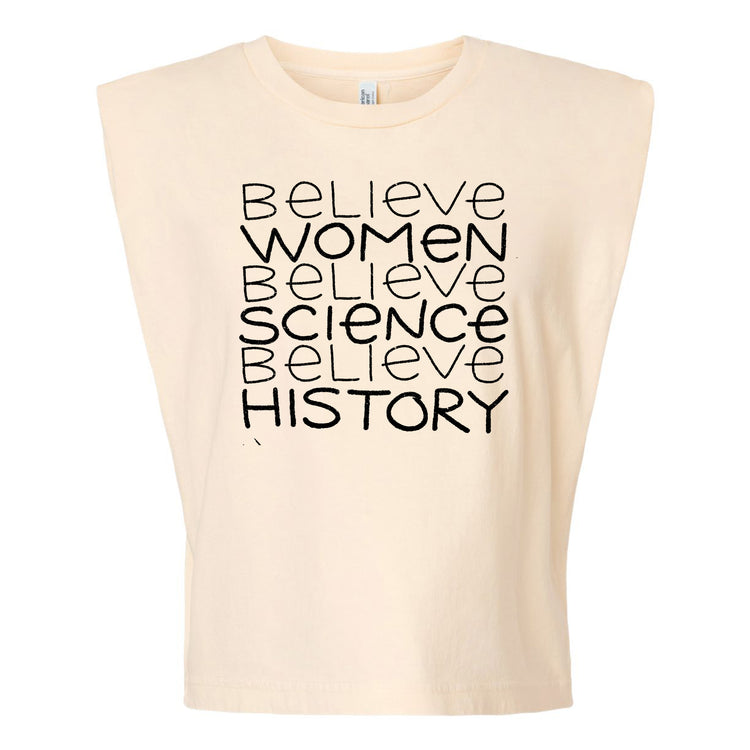 A beige t-shirt with the text "Believe Women, Believe Science, Believe History" printed on it in a vertical arrangement.