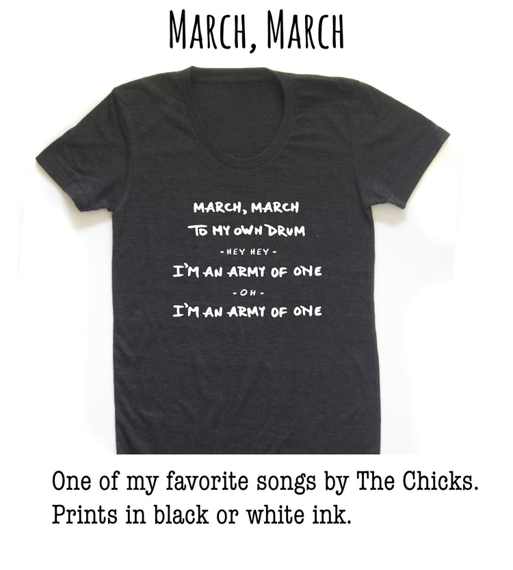 A black t-shirt with white text that reads "March, March to my own drum - Hey, I'm an army of one - Oh, I'm an army of one" printed on it.