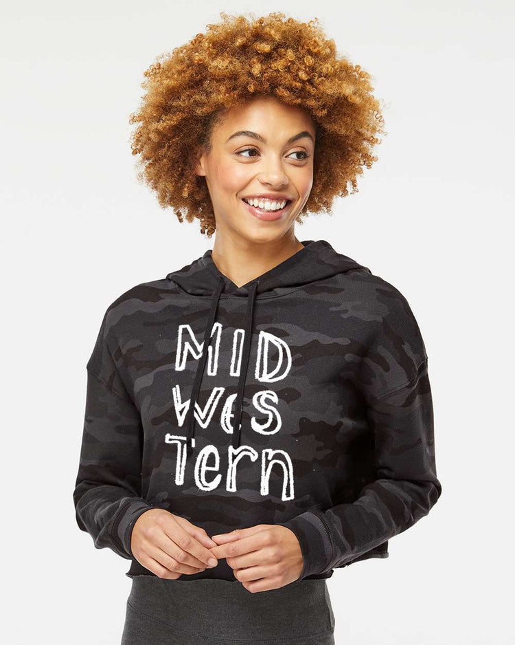 A smiling woman with curly hair wearing a black hoodie with white text on it.