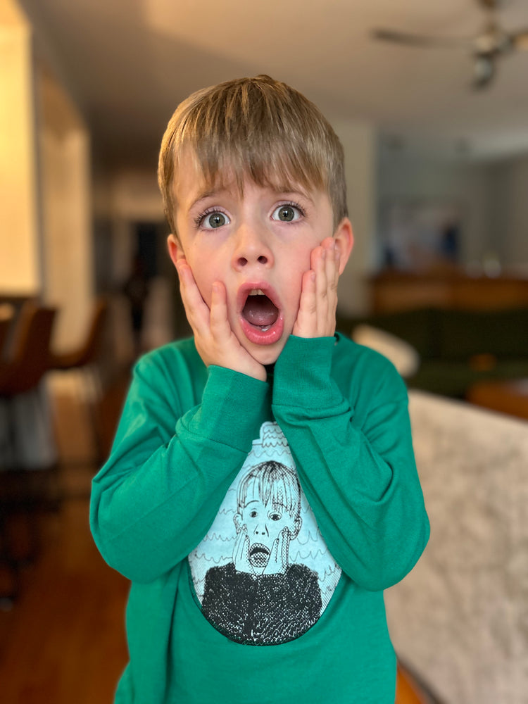 a young boy holding his hands to his face