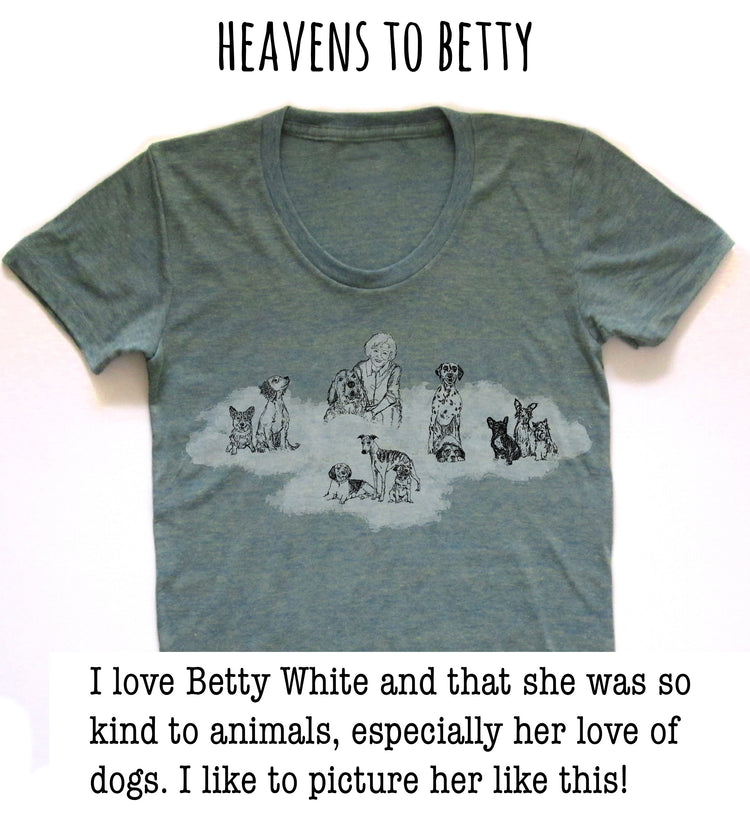 A gray t-shirt with a graphic design depicting a woman surrounded by various dogs. The text above the image reads "HEAVENS TO BETTY".