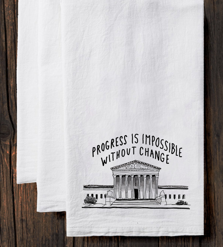 A white towel with a black and white illustration of a building and the text "Progress is Impossible Without Change" printed on it.