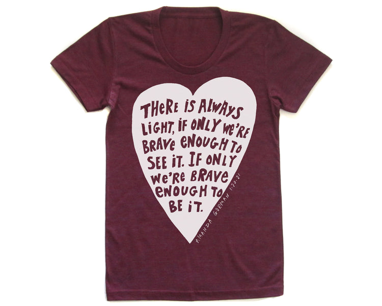 The image is a maroon t-shirt with a white heart-shaped graphic containing a quote in black text.