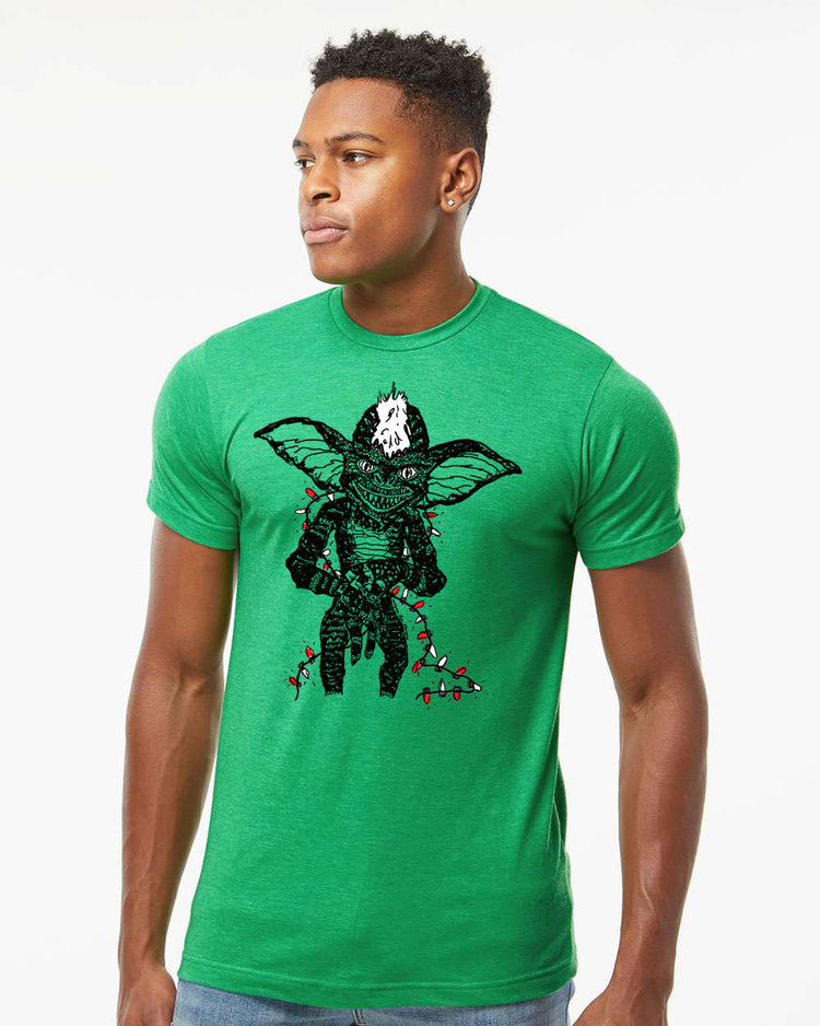 a man wearing a green t - shirt with a picture of a demon on it