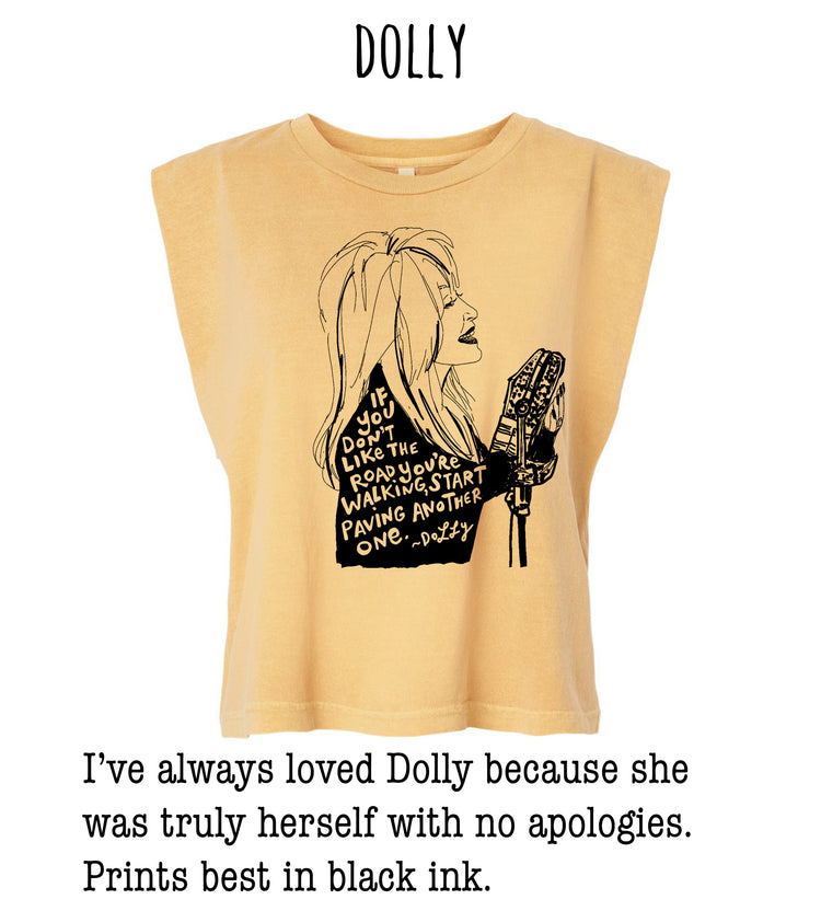 A yellow t-shirt with a black and white illustration of a woman holding a microphone and text that reads "If you don't like the road you're on, start walking down the road. Dolly"