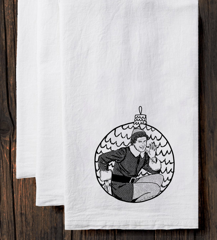 A white towel with a black and white illustration of a person sitting inside a Christmas ornament.