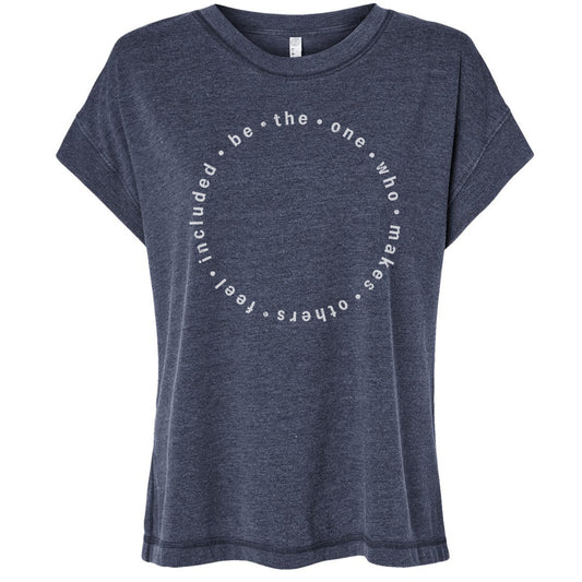 A gray t-shirt with a circular design featuring the text "be the one who makes others feel included" printed on it.