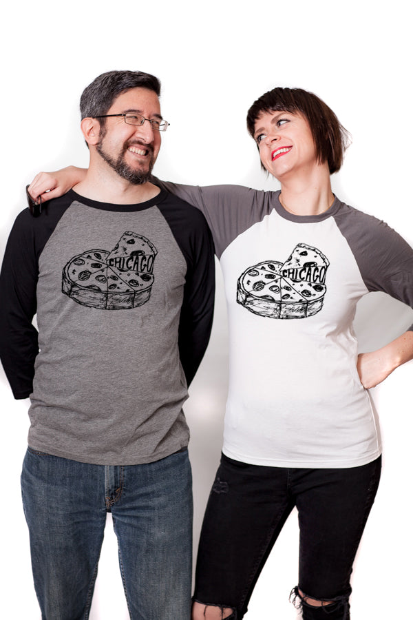 A man and a woman are standing close together, smiling and posing for a photo. They are both wearing t-shirts with a graphic of a pizza.