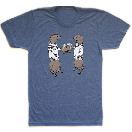 A blue t-shirt with a graphic design depicting two otters wearing sweaters and holding beer glasses, appearing to be enjoying a casual social gathering.