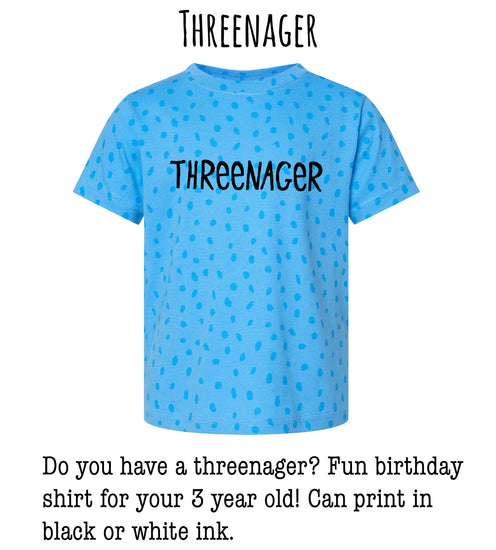 A blue t-shirt with the text "THREEENAGER" printed on it, indicating it is a shirt for a three-year-old.