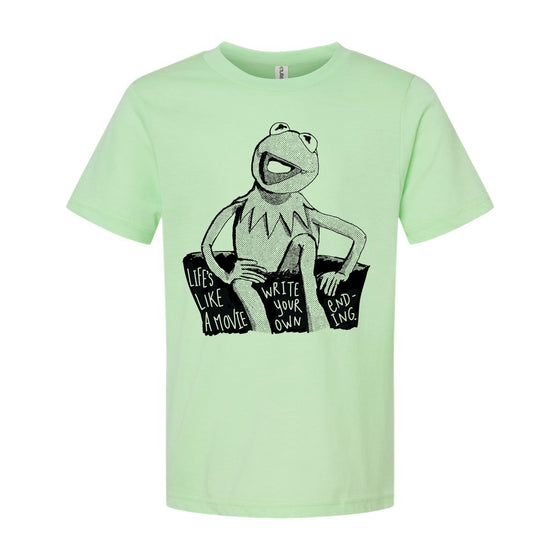 A light green t-shirt with a black and white illustration of Kermit the Frog sitting on a rock and the text "Lives like a movie, write your own ending" printed on it.