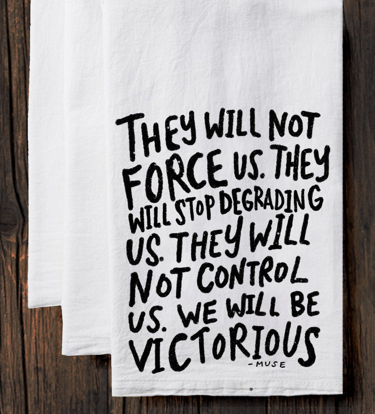 a white towel with black text that reads "They will not force us. They will stop degrading us. They will not control us. We will be victorious."