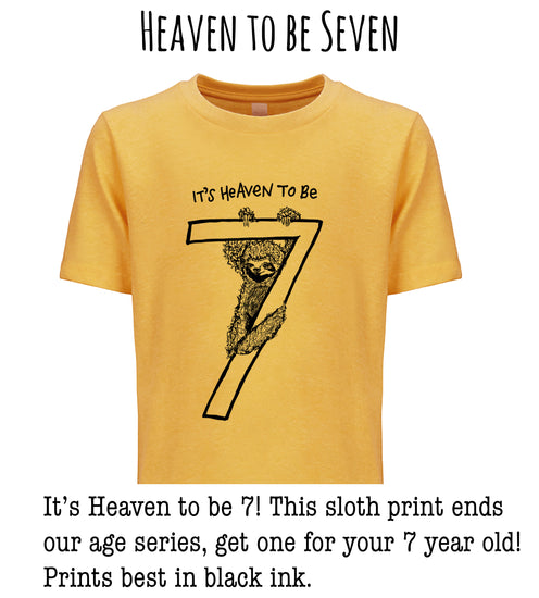 A yellow t-shirt with a black illustration of a sloth holding a number 7, accompanied by the text "It's Heaven to be 7! This sloth print ends our age series, get one for your 7 year old! Prints best in black ink."