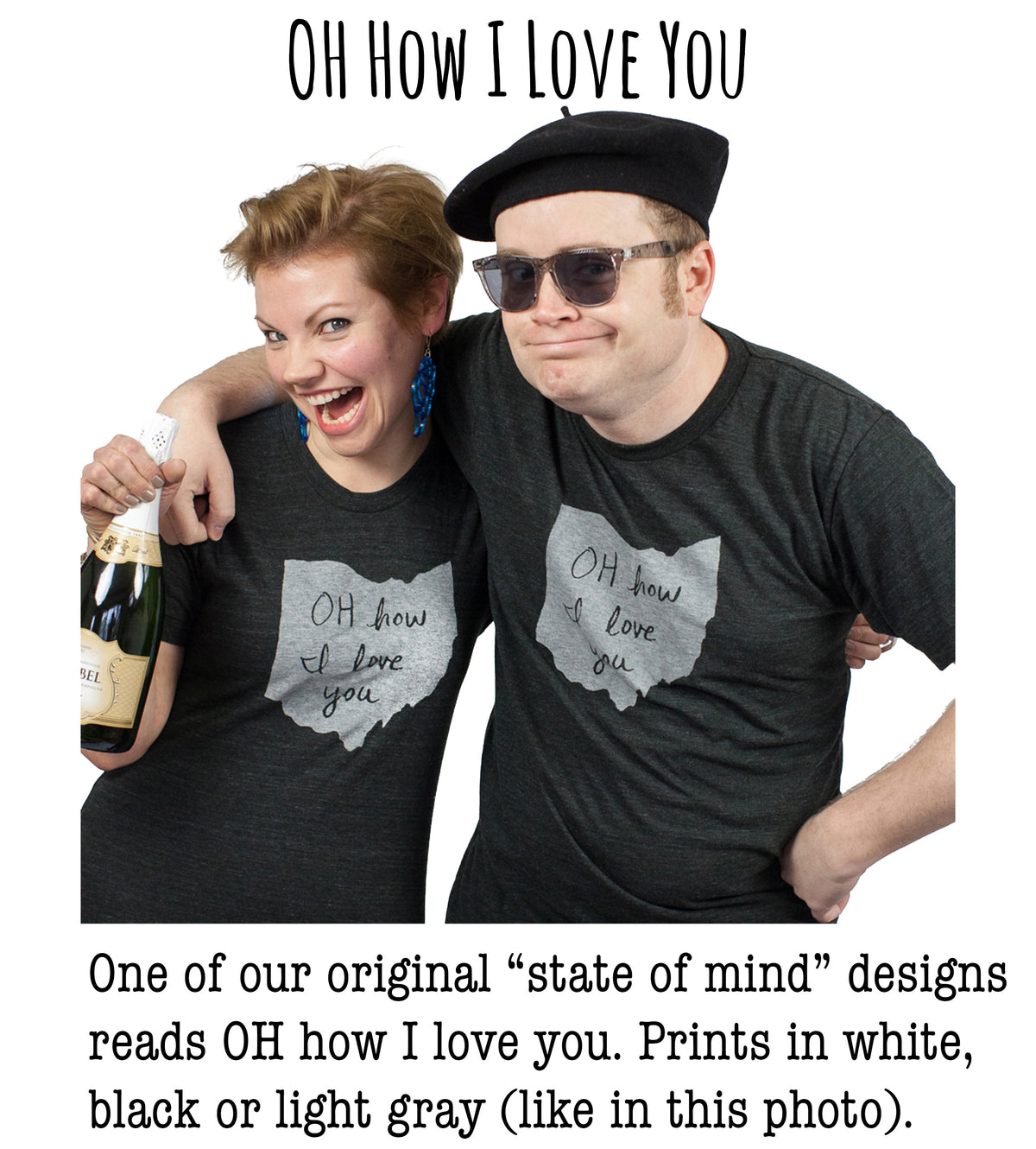 A man and a woman wearing matching black t-shirts with handwritten text, posing together and smiling.