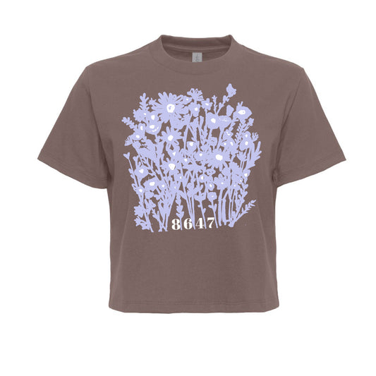 A brown t-shirt with a graphic design of purple flowers on the front.