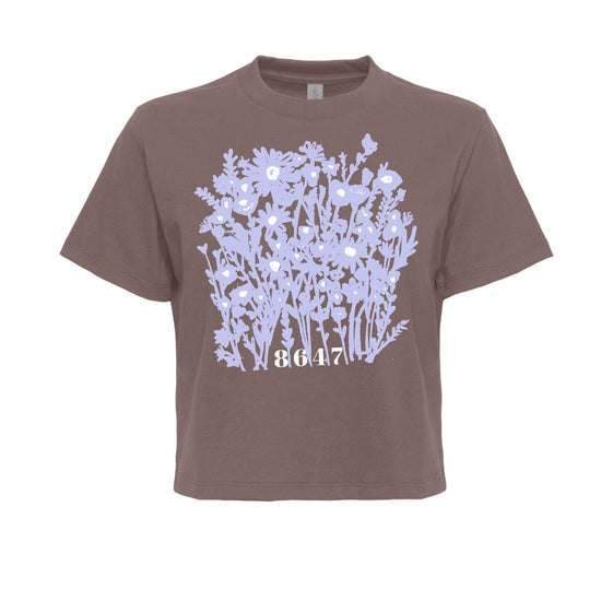 A brown t-shirt with a graphic design of purple flowers on the front.