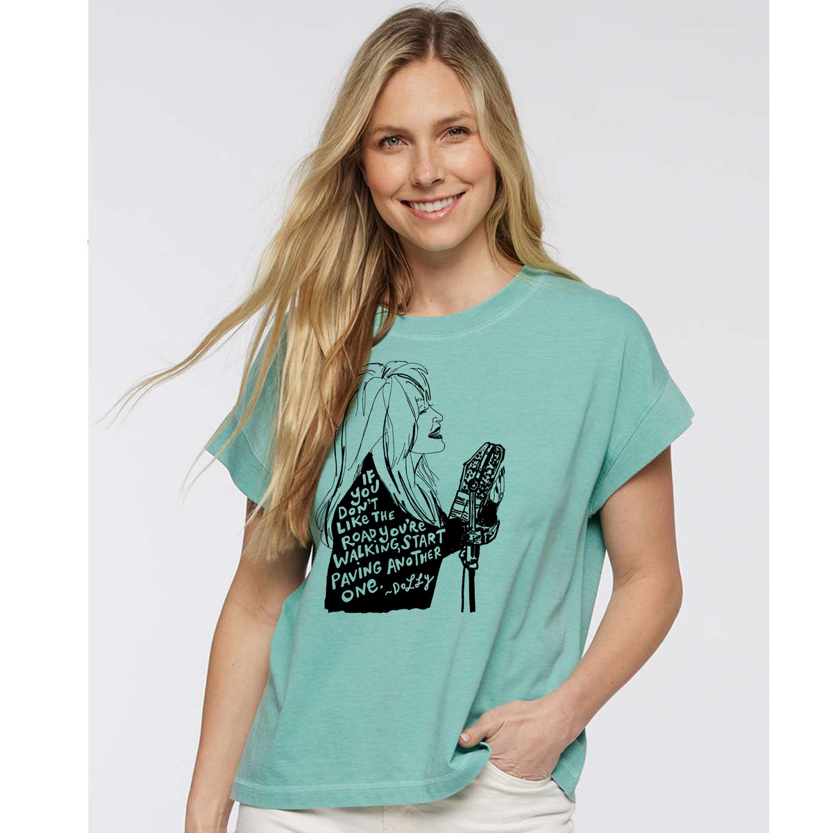 A smiling woman wearing a turquoise t-shirt with a graphic design on it.