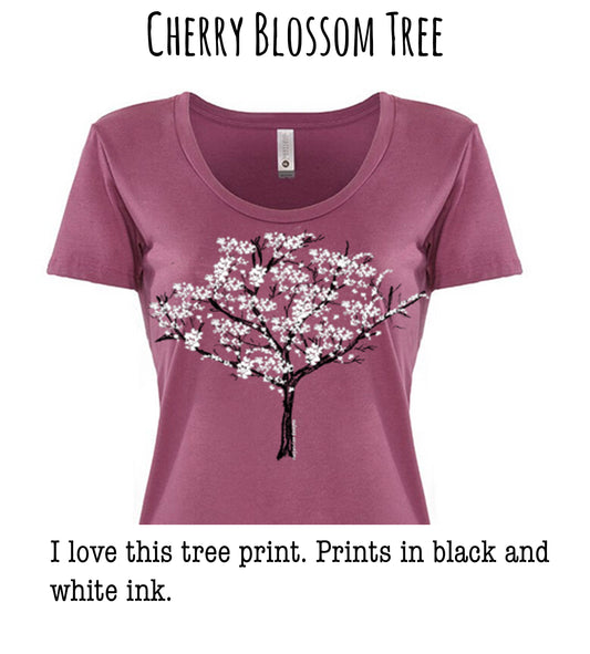 A pink t-shirt with a cherry blossom tree design printed on it.