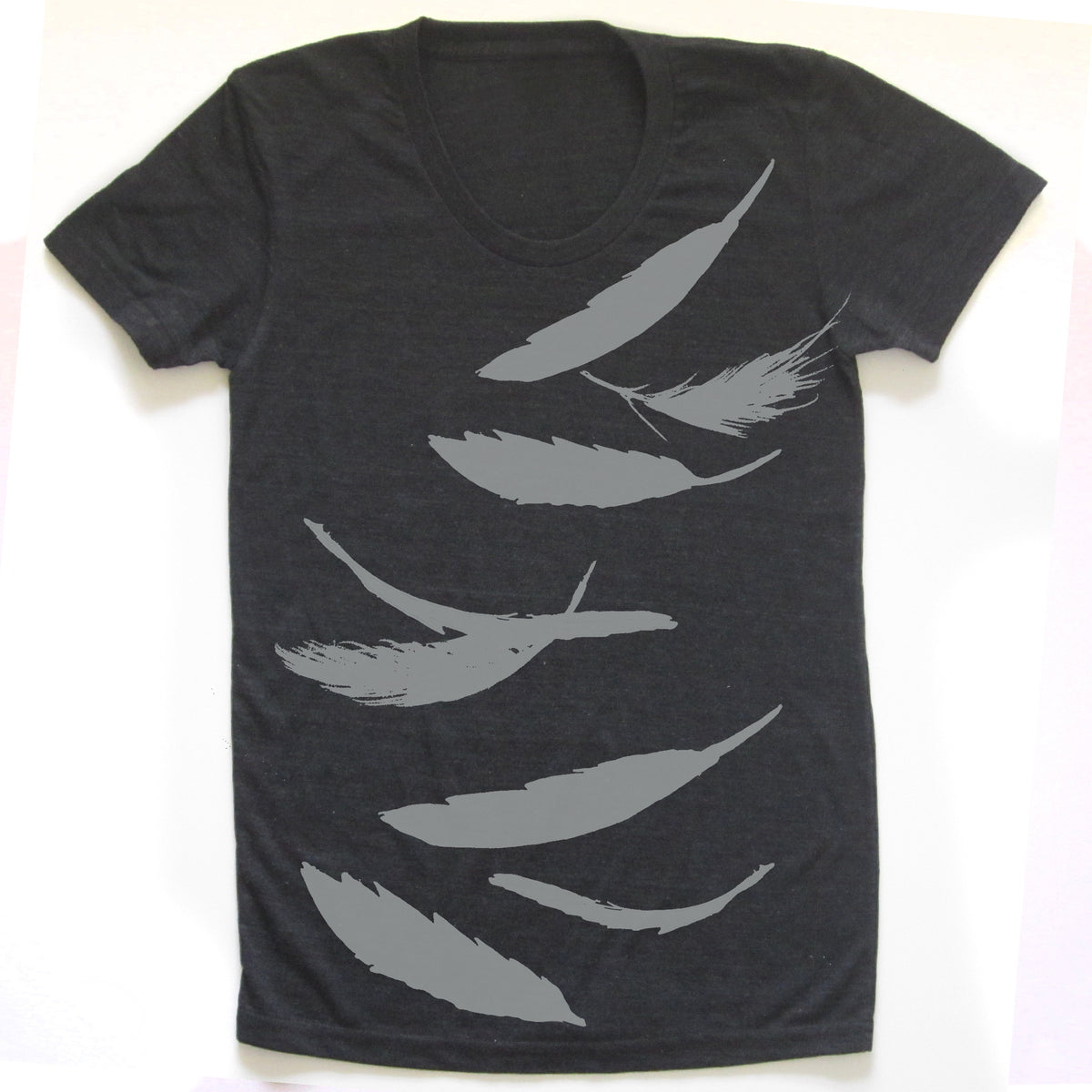 A black t-shirt with a graphic design of white feather silhouettes printed on it.