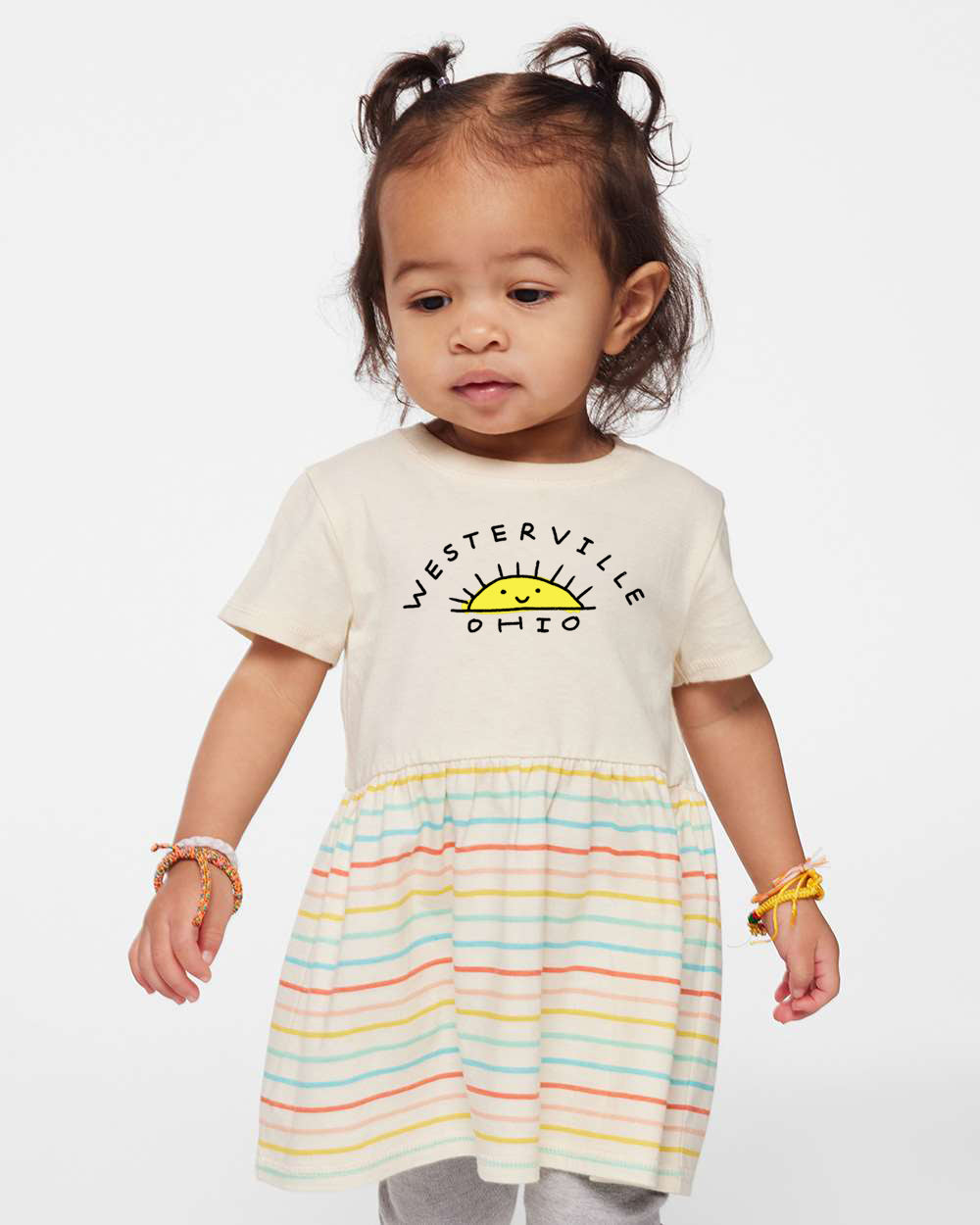 A young girl wearing a white t-shirt with the text "WESTERVILLE PHO" and a striped skirt, standing against a white background.