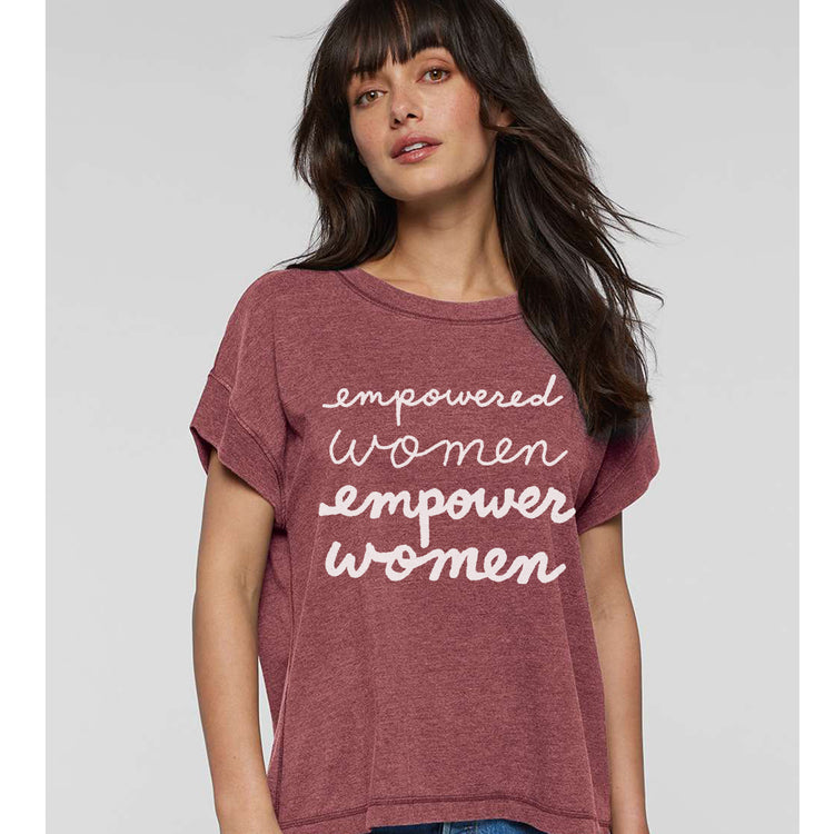 A woman wearing a maroon t-shirt with the text "empowered women empower women" printed on it.
