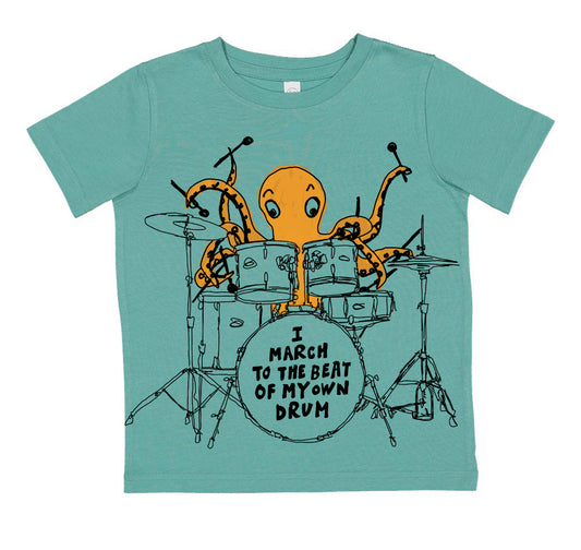 A t-shirt with an illustration of an orange octopus playing a drum set, accompanied by the text "I M March to the Beat of My Own Drum".