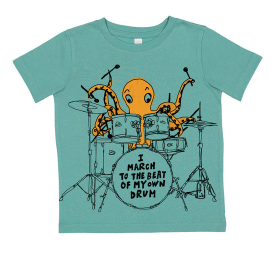 A t-shirt with an illustration of an orange octopus playing a drum set, accompanied by the text "I M March to the Beat of My Own Drum".