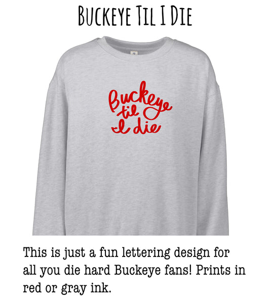 This image features a gray sweatshirt with a red text design that says "Buckeye til I die". The text is a playful and humorous phrase that is likely intended to be humorous to Buckeye fans.