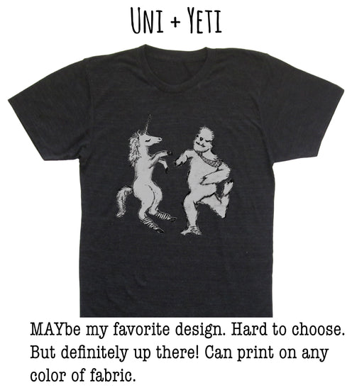 A black t-shirt with a graphic design depicting a unicorn and a creature resembling a bear or dragon. The text above the image reads "UNI + YETI".