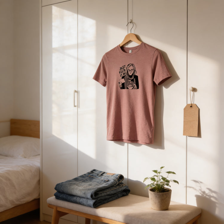 a pink t-shirt hanging on a wooden hanger, with a pair of jeans and a potted plant placed on a bench in the foreground.
