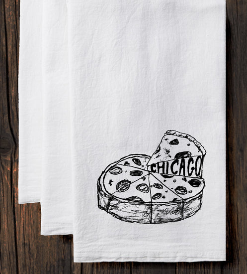 A white towel with a black and white illustration of a slice of pizza with the word "CHICAGO" written on it.