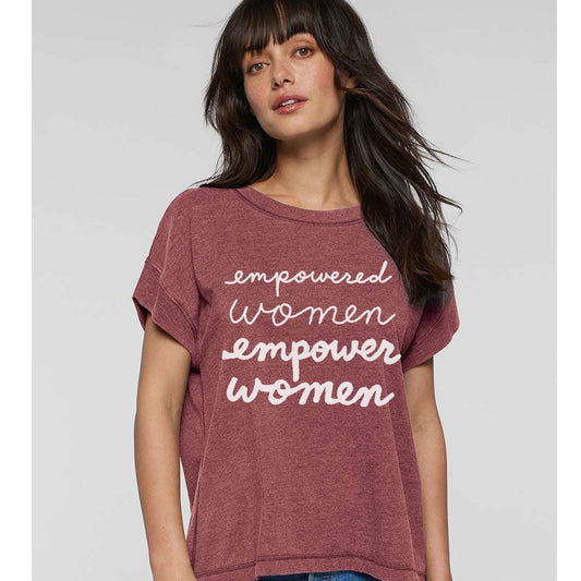 A woman wearing a maroon t-shirt with the text "empowered women empower women" printed on it.