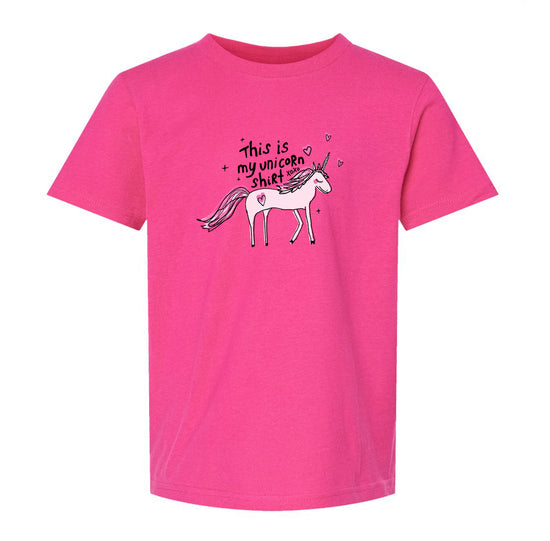 A pink t-shirt with a graphic of a unicorn and the text "This is my unicorn shirt" printed on it.