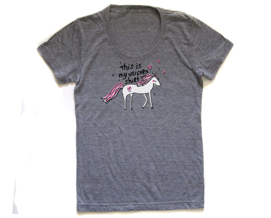 The image is a gray t-shirt with a graphic design of a white unicorn and pink hearts.