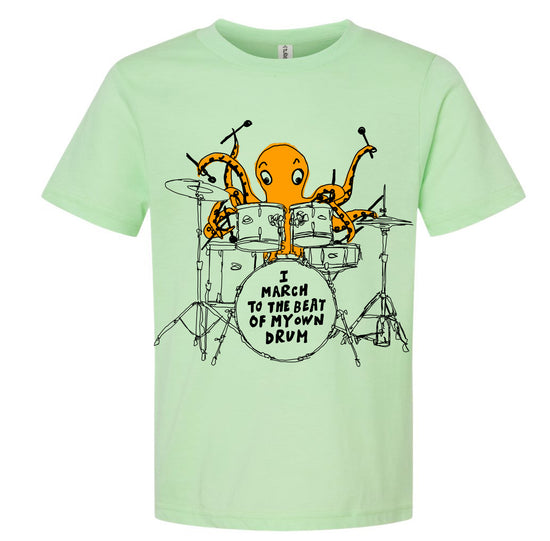 An orange octopus is playing a drum set, with the text "I MARCH TO THE BEAT OF MY OWN DRUM" displayed on the t-shirt.