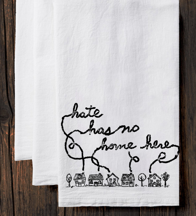 A white towel with a black handwritten text and a small illustration of houses on it.